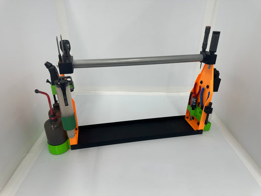 A 3D-printed DIY tool holder and workbench organizer, featuring a black base, orange and green side brackets, a silver metal bar, and various small hand tools, shown on a white background.